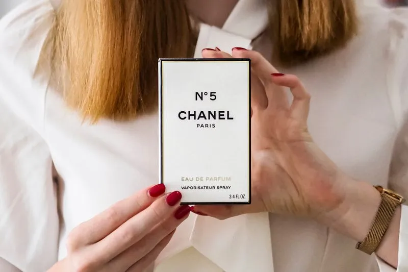 Two hands hold a perfume box, with the 'Eau de Parfum' wording and volume shown on the front