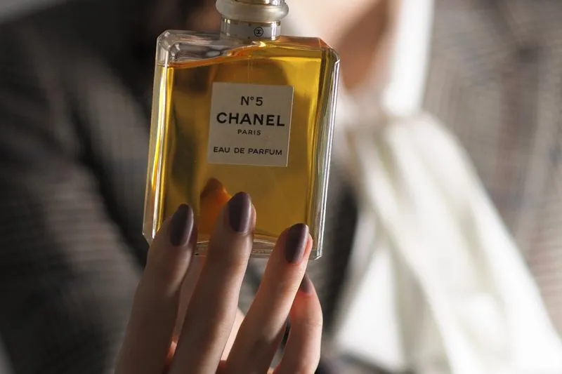 Hand holding a perfume bottle whose label clearly reads 'Eau de Parfum'