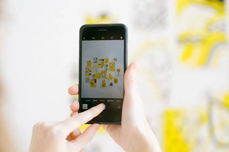 Close-up of hands photographing a wall with a smartphone, the camera app open on screen