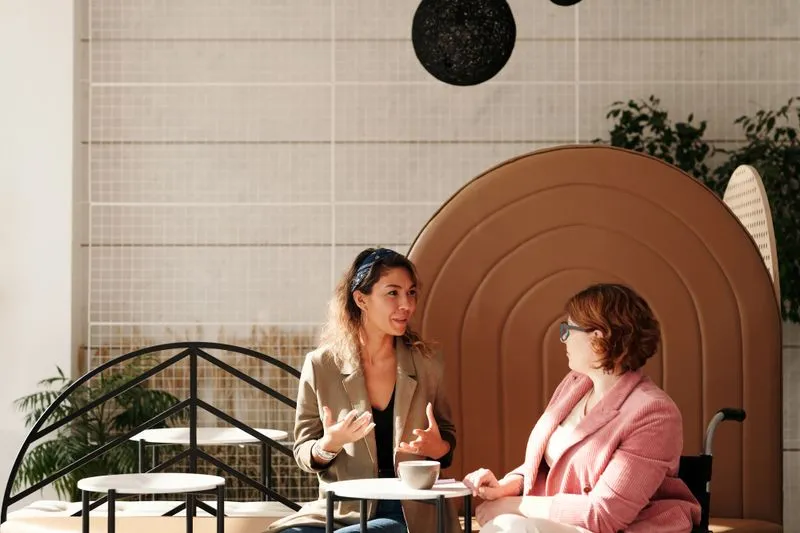 Two young women chatting animatedly over a cup of coffee