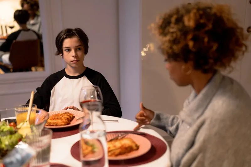 Mother and teenage son at the dinner table, deep in discussion