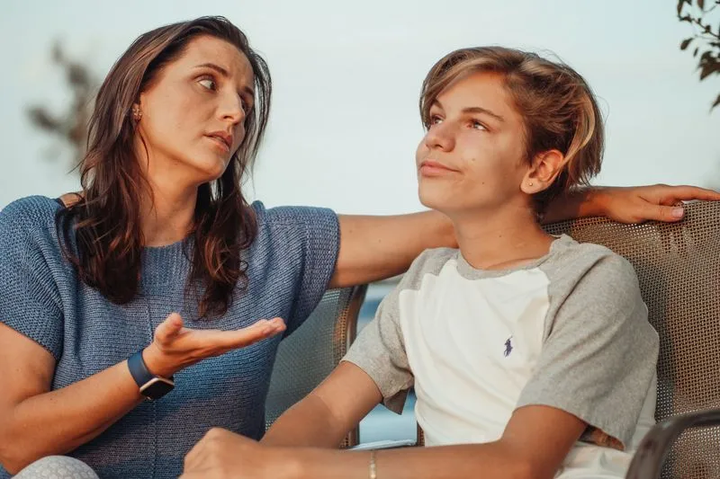 Mother and teenage son sitting side by side, deep in conversation