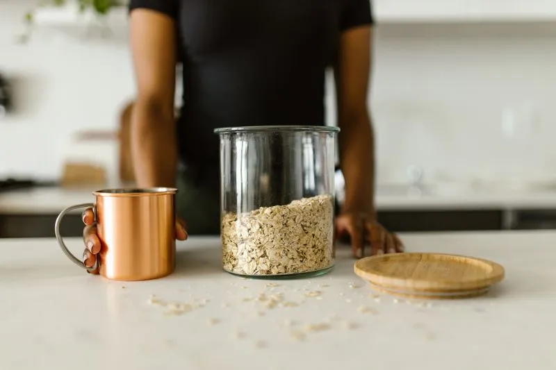Glass jar filled with oats, next to a copper mug