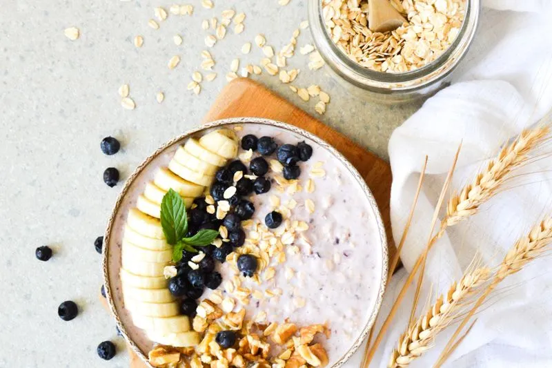Bowl of porridge topped with banana, blueberries and walnuts, seen from above