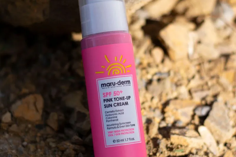 Close-up of a pink sunscreen tube with its SPF and active ingredients shown on the label