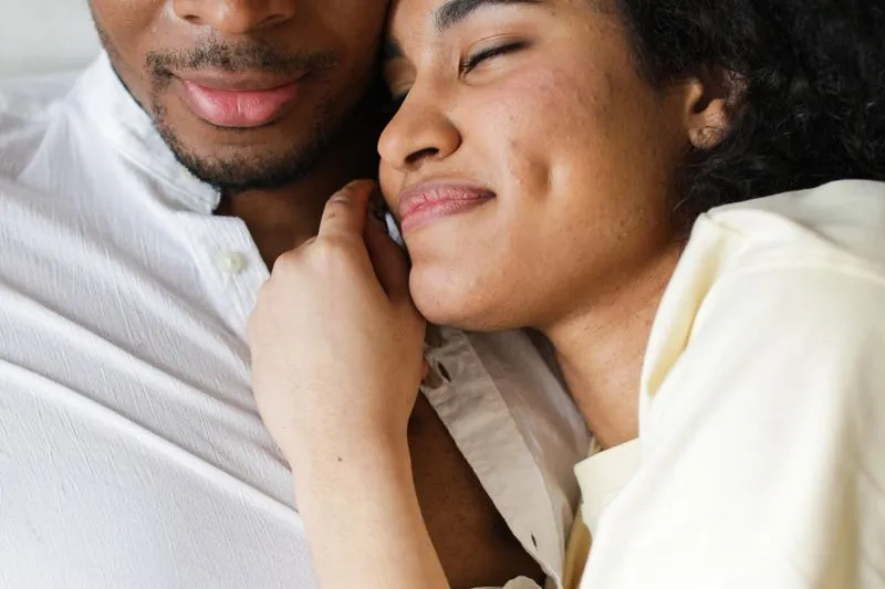 A couple nestled close together, her eyes closed against his cheek