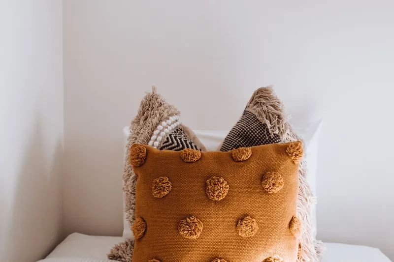 Several cushions of different sizes on a bed with white sheets