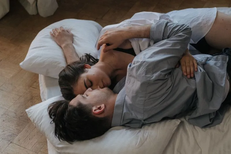 A couple embracing on pillows on the floor, his face against her cheek