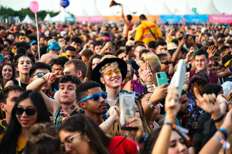 Outdoor music festival crowd in the afternoon, with several festival-goers wearing round, colourful sunglasses
