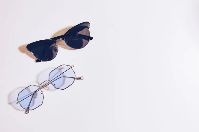 Two pairs of glasses with lenses of different darkness on a white surface