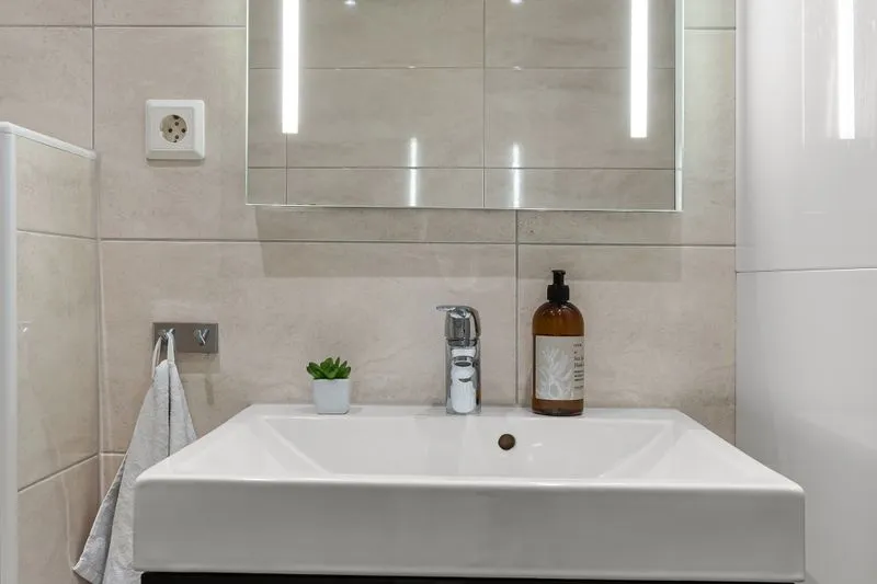 Bathroom mirror framed by LED light strips on each side, above a basin