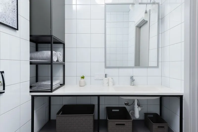 Black wall shelf holding folded towels, beside a vanity counter with storage baskets