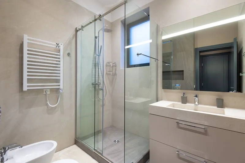 Shower enclosed by a sliding glass screen in a tiled bathroom
