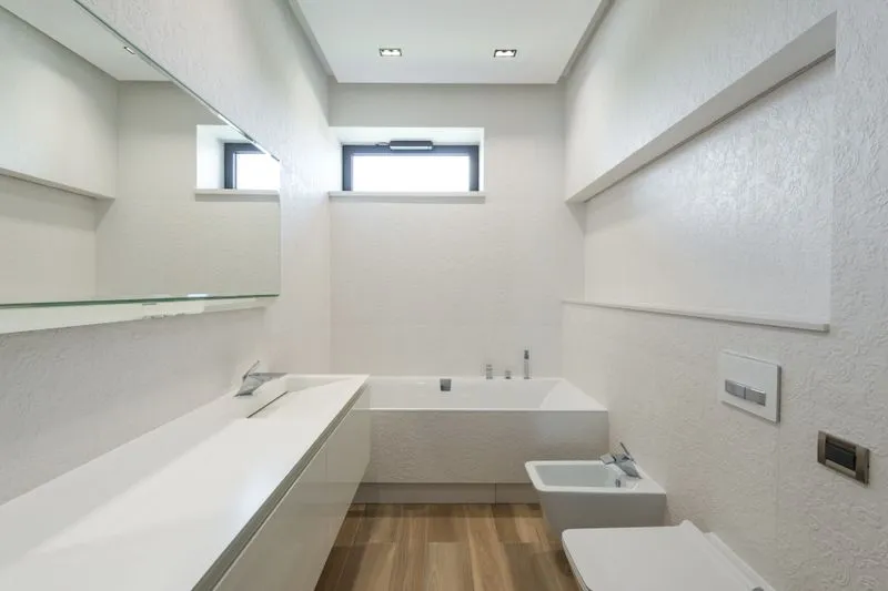 Bathroom with white walls from floor to ceiling, a small window, a bathtub and a basin