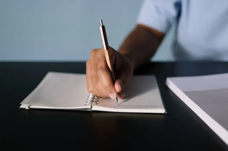 Hand writing with a pen in an open spiral notebook