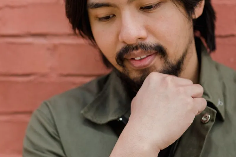Close-up of a man with a short beard, his fist resting under his chin