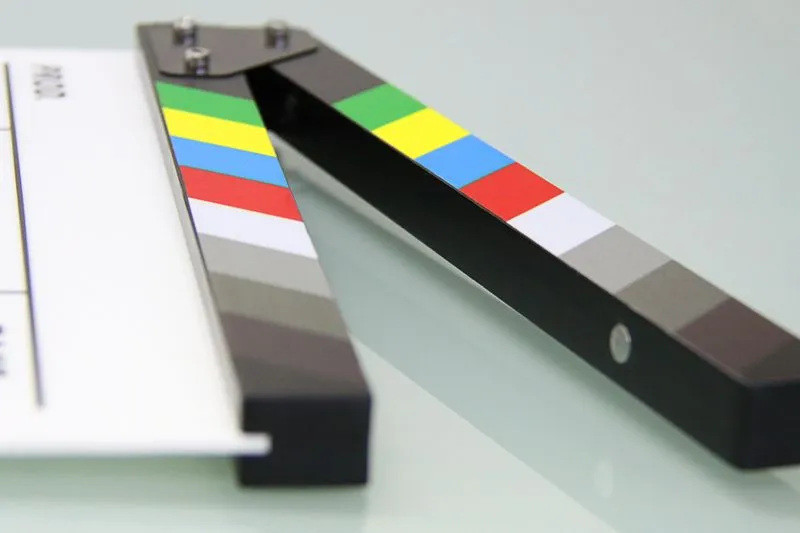 Close-up of a film clapperboard lying open on a reflective surface