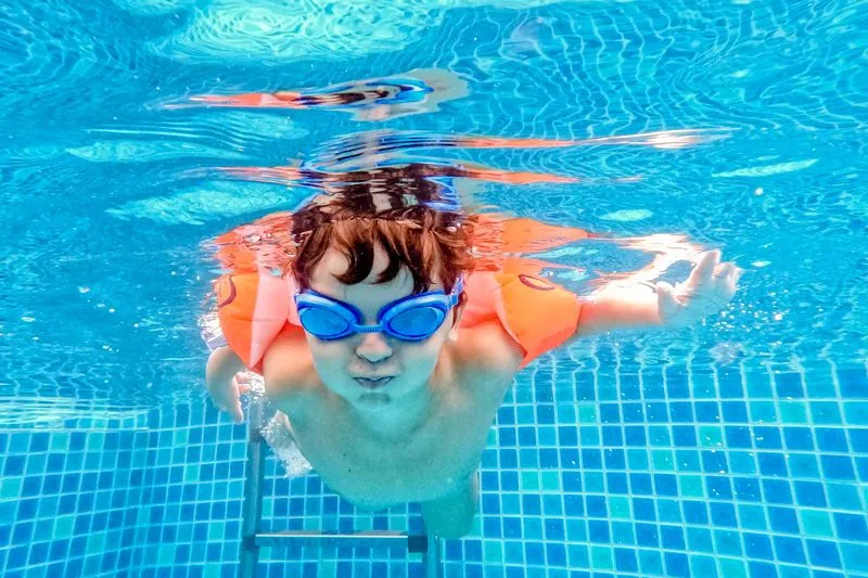 Child wearing inflatable armbands in a swimming pool