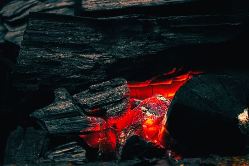 Close-up of glowing charcoal embers, deep red, with no flame visible
