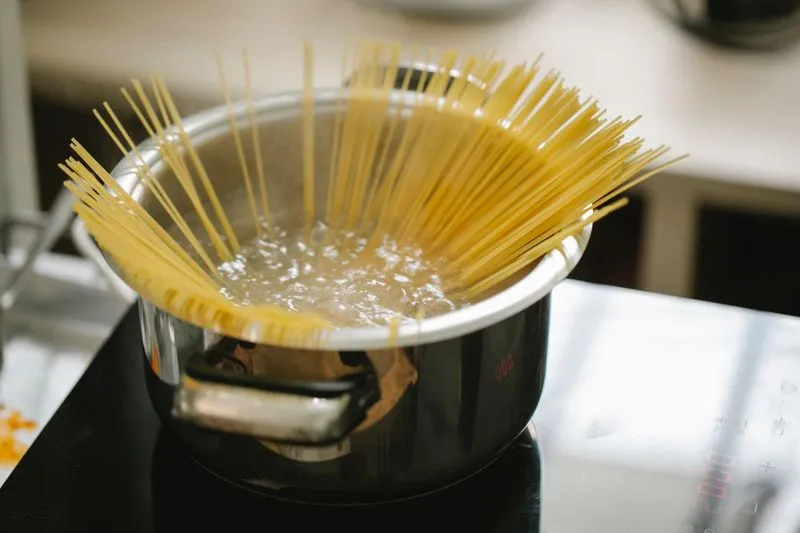 Spaghetti sticking up out of a pan of boiling water on the hob