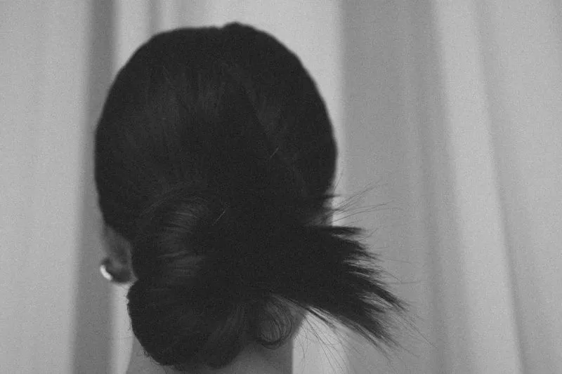 Back view of a low, slightly twisted bun in black and white, with a few loose wisps at the base