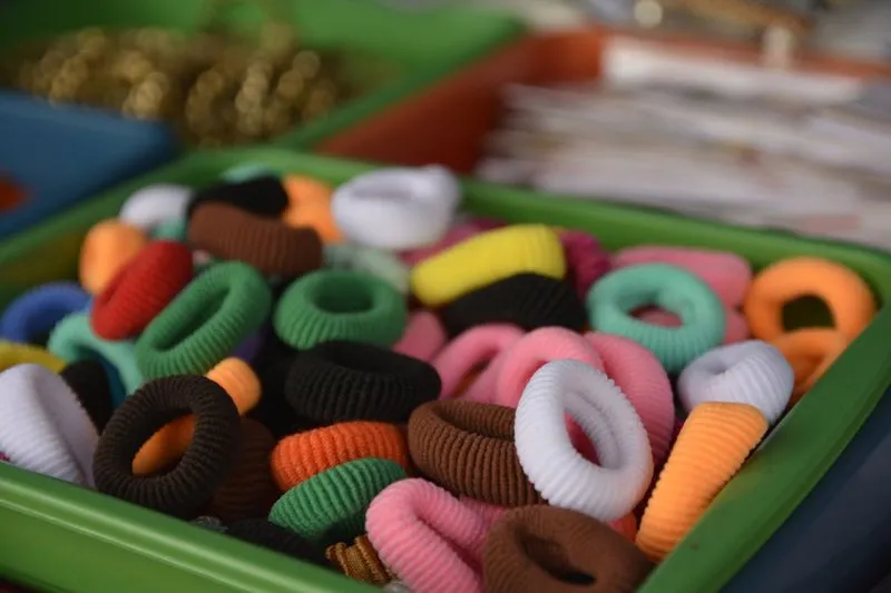 Dozens of fabric-covered hair ties in every colour, piled in a green tray