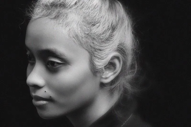 Profile of a woman with her hair swept back, a few loose strands around her face, in black and white