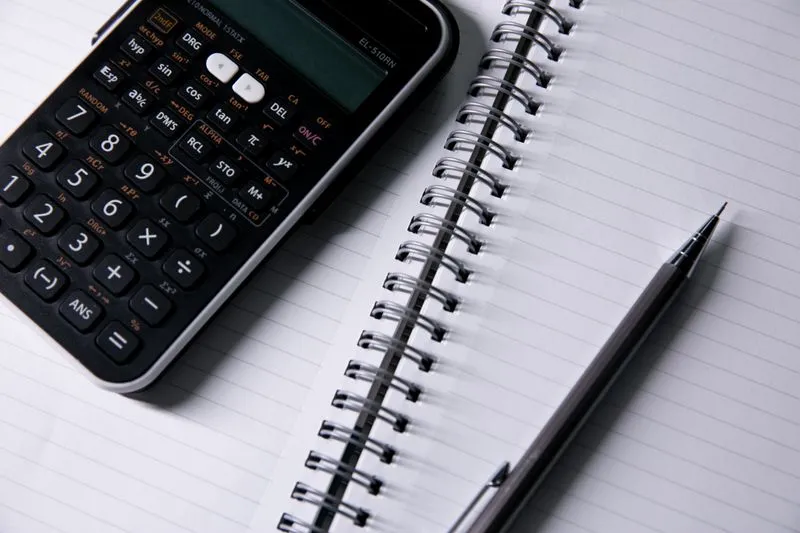 Blank spiral notebook, a calculator and a pen on a table