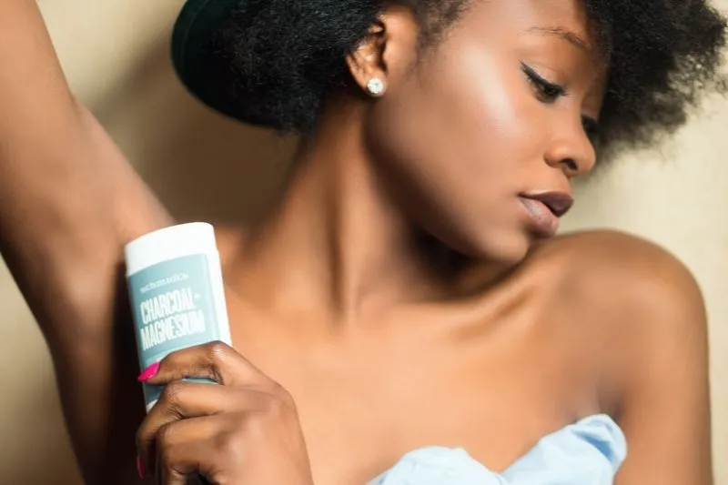 Close-up of a young woman applying a stick deodorant under her arm