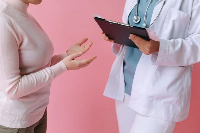 A woman talking with a healthcare professional in a white coat holding a folder