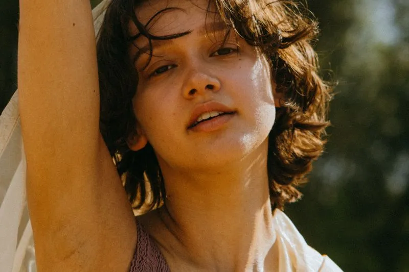 Close-up of a young woman with her arm raised in warm early-evening summer light