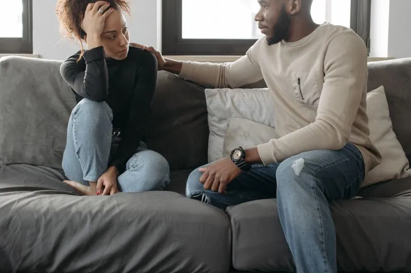 Young couple sitting on a sofa, turned towards each other, in the middle of a serious conversation