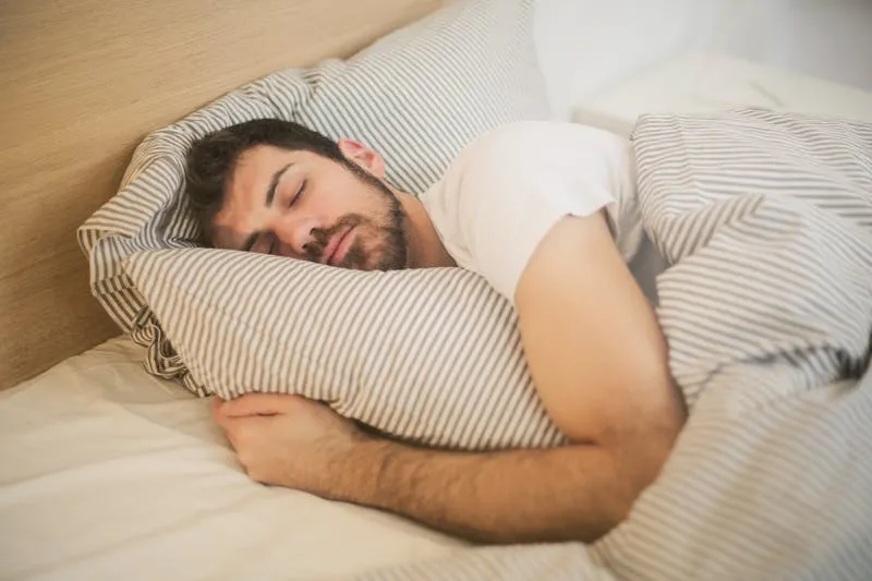 Woman sleeping peacefully with alarm clock on bedside table