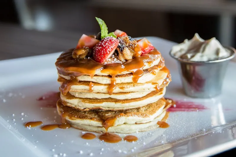 Stack of fluffy pancakes with berries and maple syrup