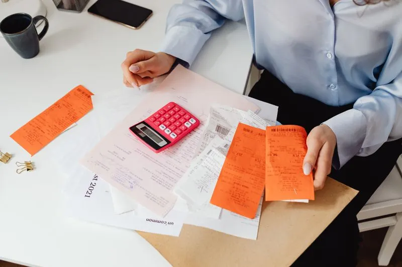 A woman sorting receipts next to a calculator to work out a moving budget