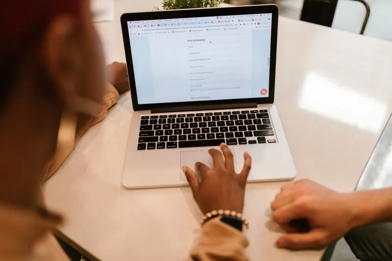 Two people filling in an online form on a laptop