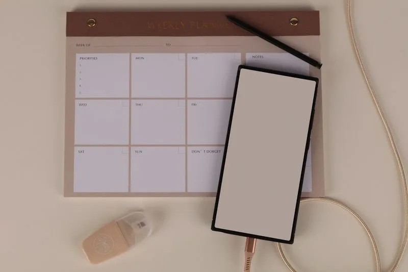A blank weekly planner, a pen and a phone for mapping out moving tasks