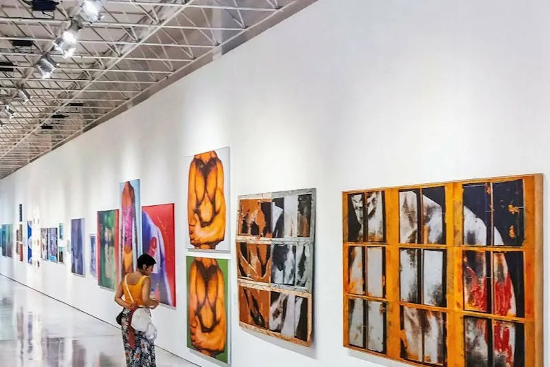 Visitor contemplating a painting in a bright art gallery