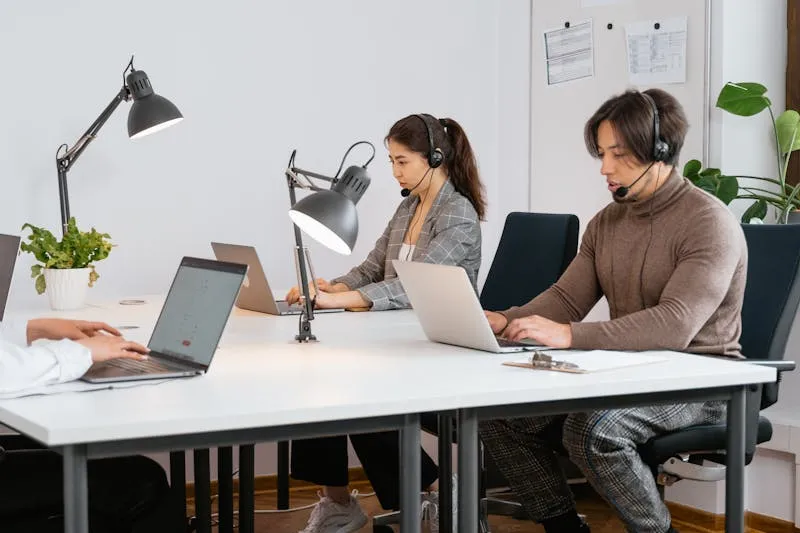 Woman and man side by side at a computer in an open-plan office